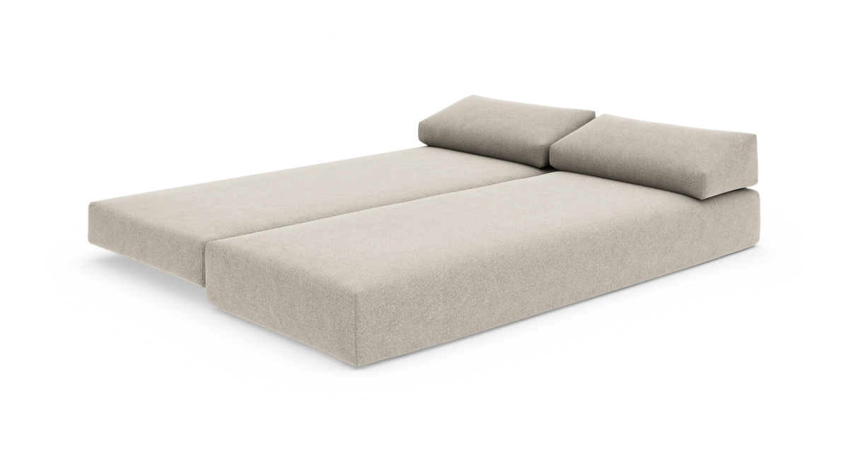 Beige modulsofa udfoldet til dobbeltseng med to ryghynder, fritlagt på hvid baggrund.