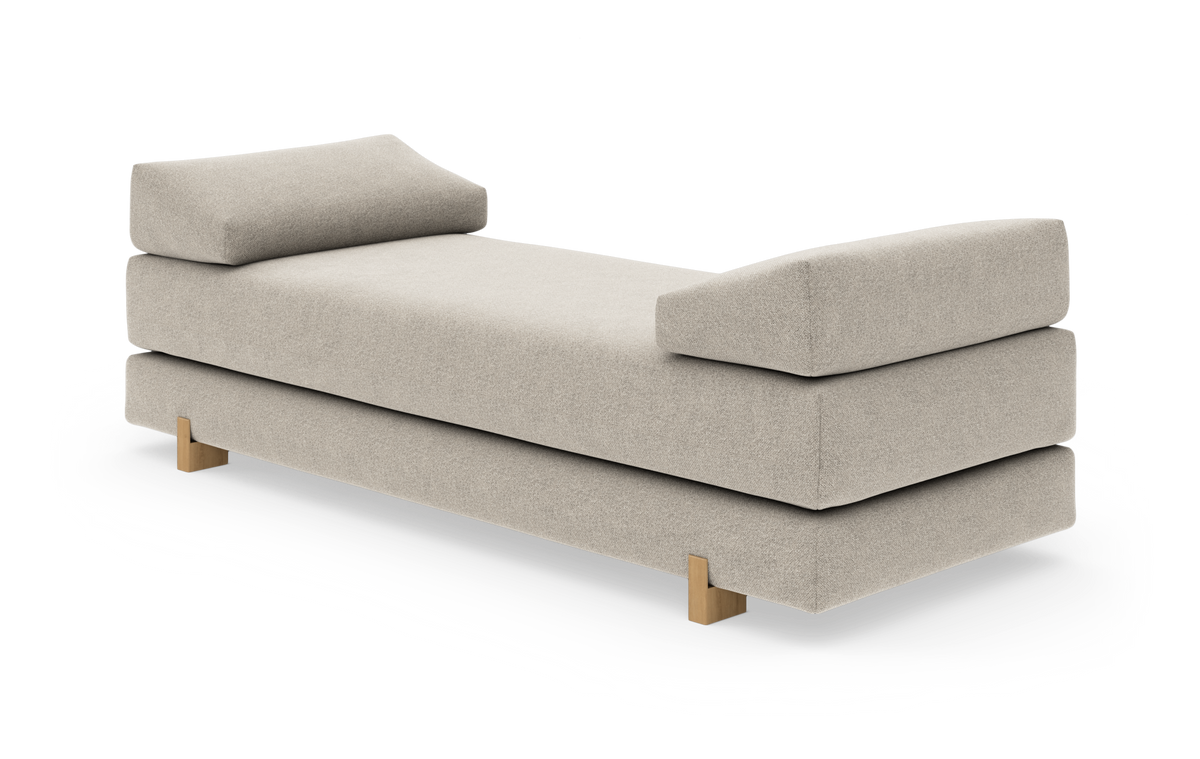 Beige daybed med to skrå, polstrede armlæn og træben, frilagt på hvid baggrund.