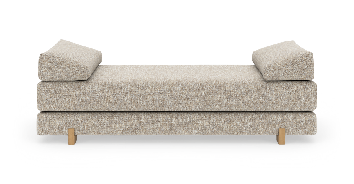 Beigefarvet daybed/sofa med to vinklede hovedpuder og små træben, set lige forfra på hvid baggrund.