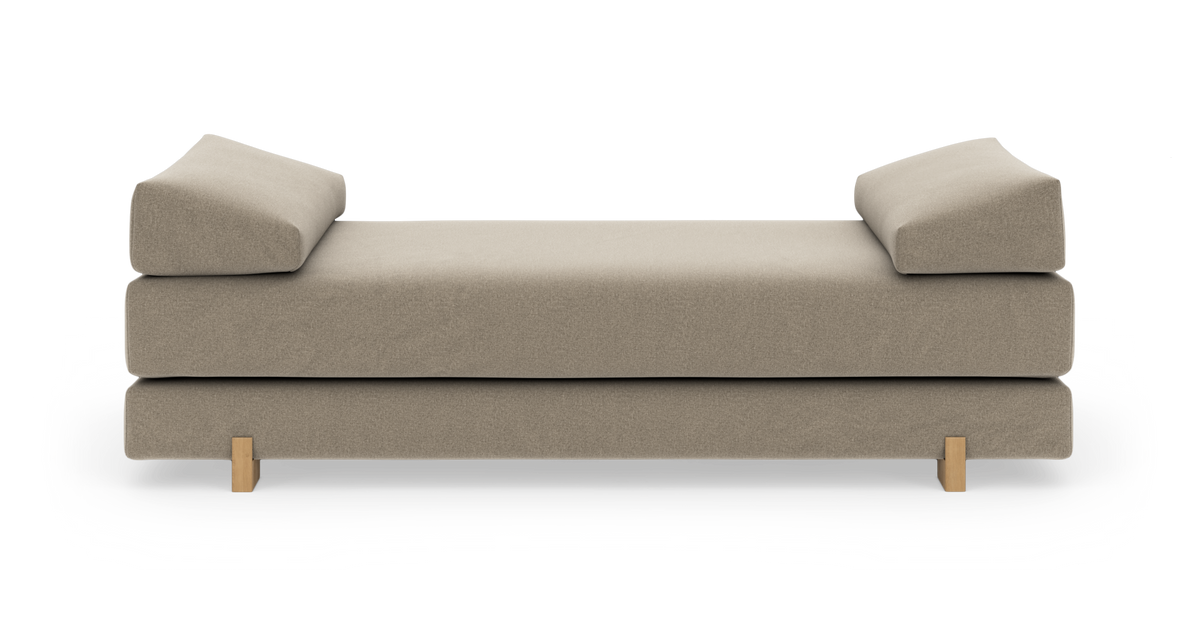 Beige moderne daybed med to vinklede ryghynder og lyse træben, frilagt på hvid baggrund.