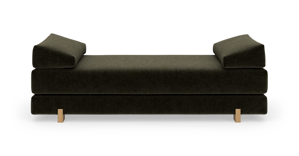 Mørkegrøn daybed/sofa med skrå ryghynder og træben, fotograferet lige forfra på hvid baggrund.