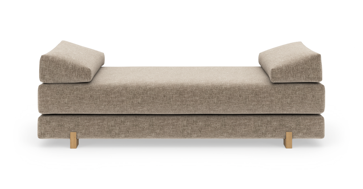 Beige daybed med vinklede armlænspuder og træben, fritlagt på hvid baggrund.