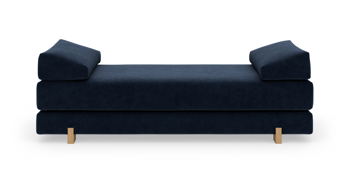 Mørkeblå daybed/sofa med lave træben, set forfra mod hvid baggrund.