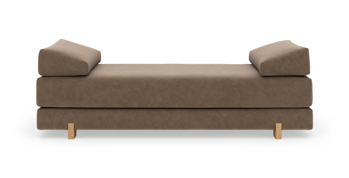 Brun daybed/sofa med to skrånende ryghynder og lyse træben, frilagt på hvid baggrund, set lige forfra.