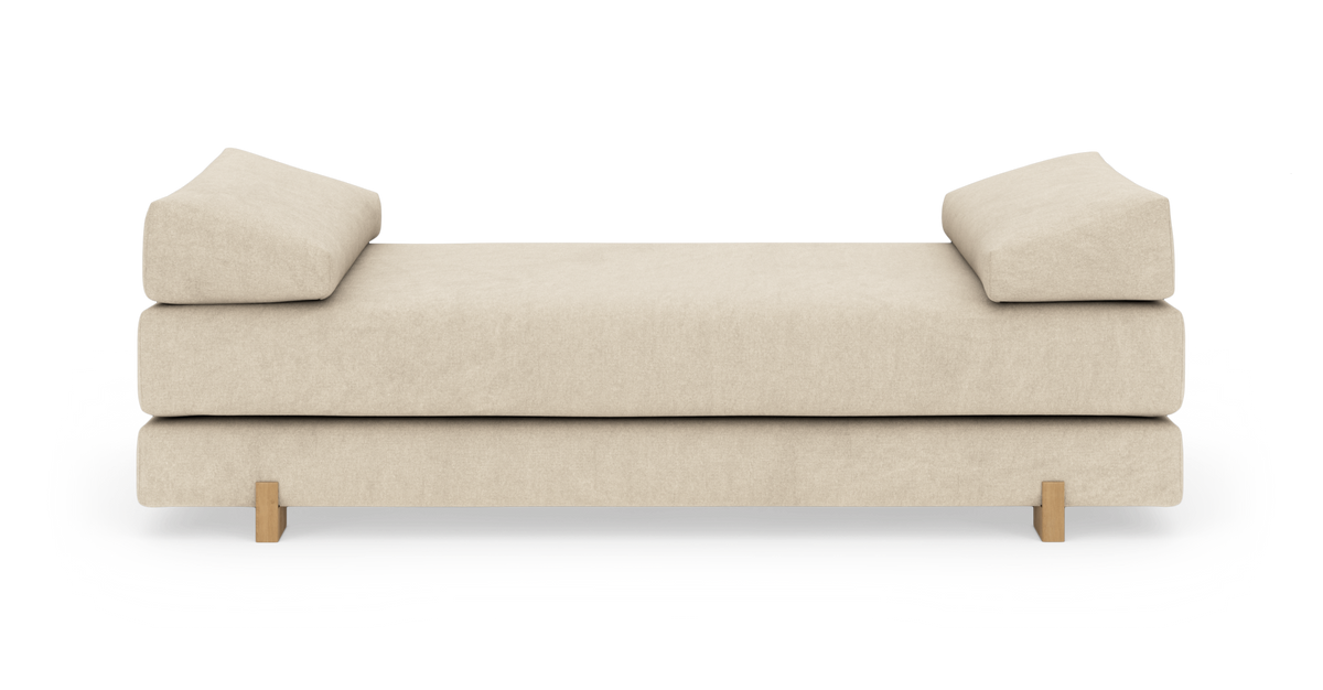 Beige daybed med to vinklede rygpuder og træben, frilagt på hvid baggrund.