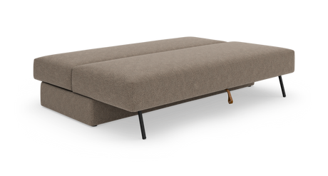 Beige sovesofa i udslået position med slanke sorte metalben, fritlagt på hvid baggrund.