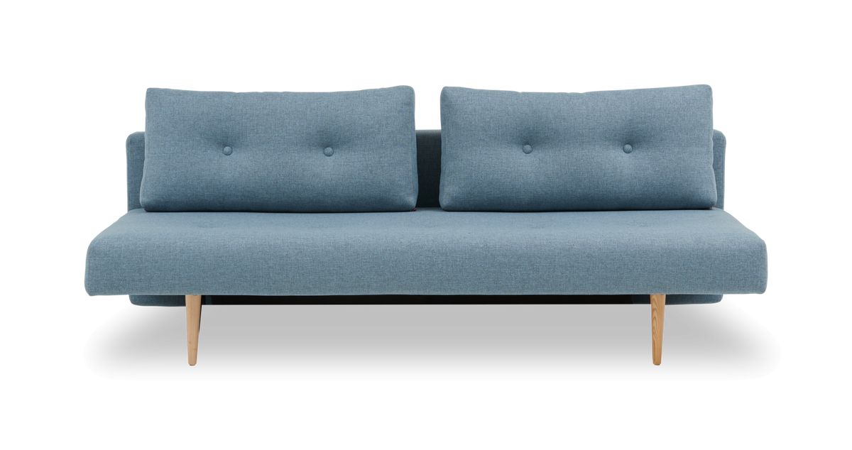 Blå to-personers sofa med knapper og lyse træben, frilagt mod hvid baggrund.