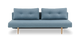 Blå to-personers sofa med knapper og lyse træben, frilagt mod hvid baggrund.