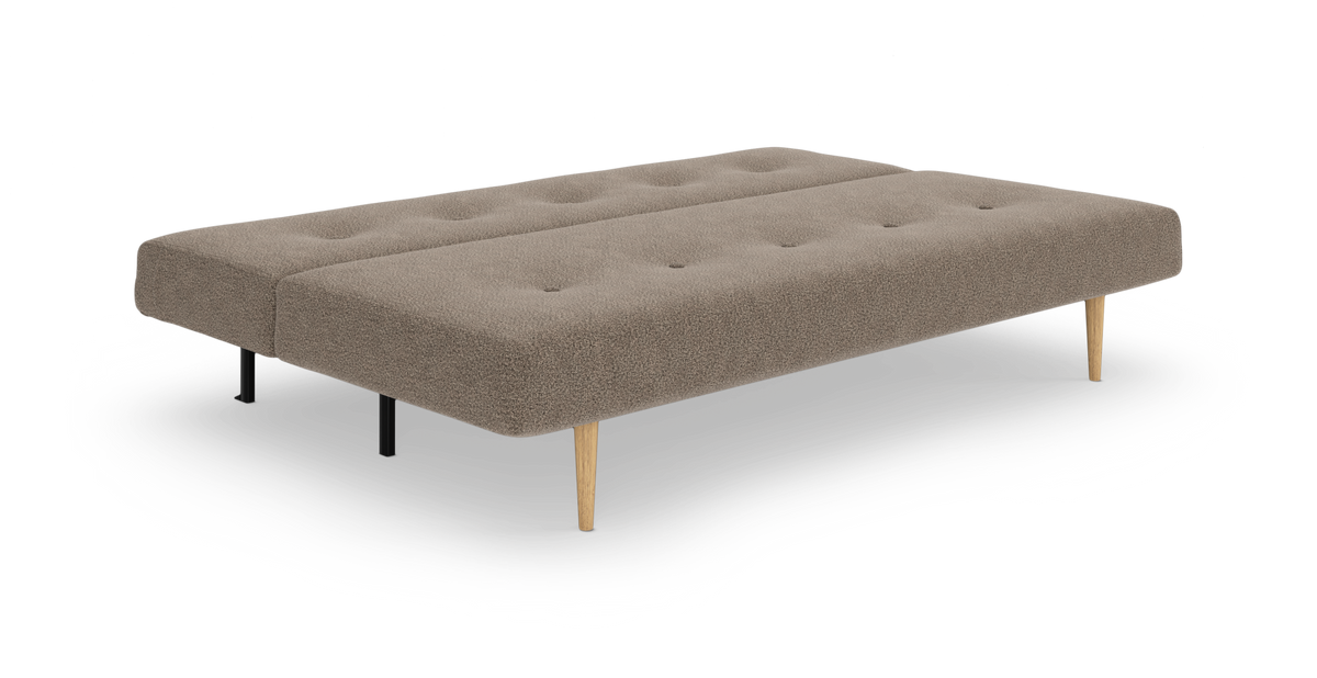 Beige sovesofa/daybed i stof med knapstikninger og koniske træben samt sorte støtteben, frilagt produktbillede i skrå frontvinkel.