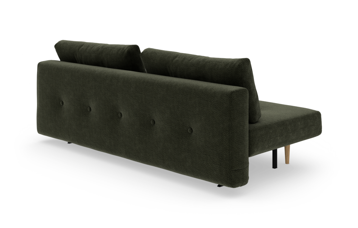 Mørkegrøn modulsofa set skråt bagfra på hvid studiebaggrund.