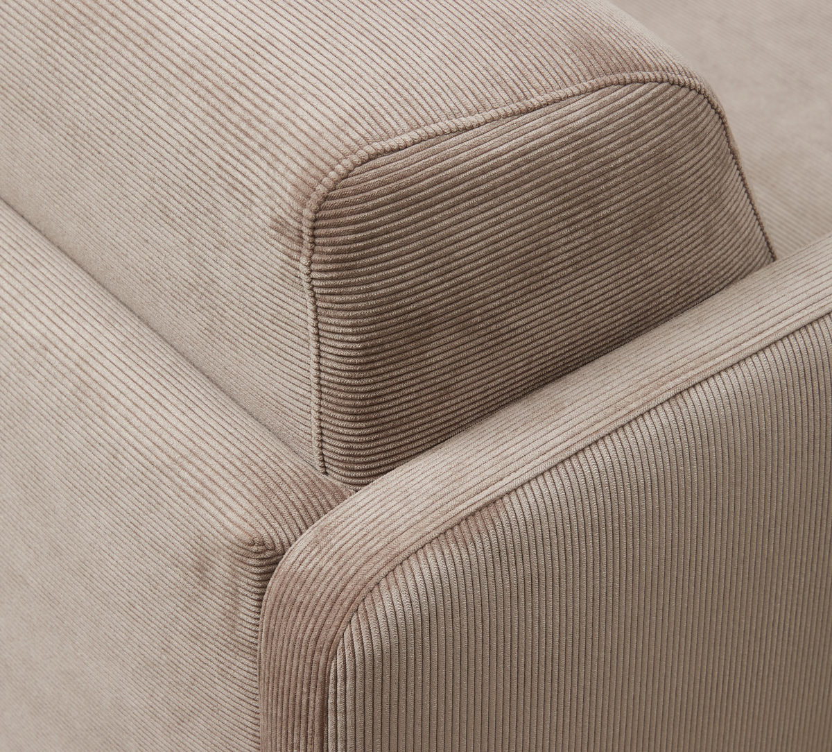 Nærbillede af beige cordfløjl-betrukket sofaarm og ryglæn.