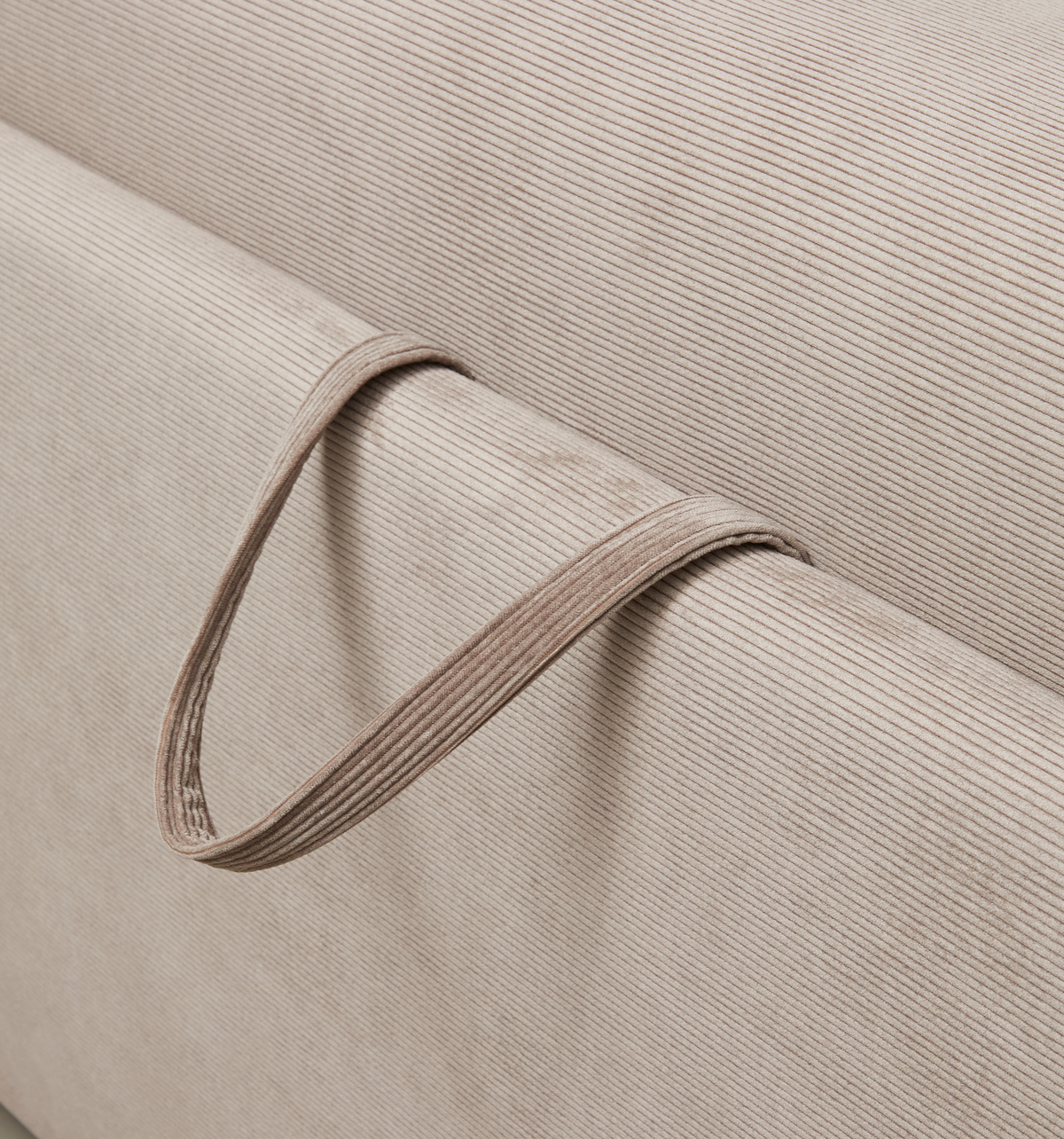 Nærbillede af beige, rillet tekstil med en smal stofløkke i samme materiale.