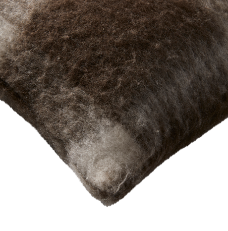 Nærbillede af brun-grå, fluffy pude med uldet tekstur på hvid baggrund.