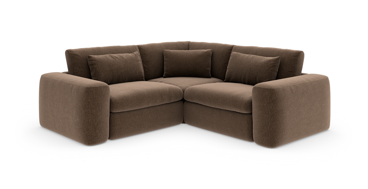Brun hjørnesofa med bløde, afrundede armlæn og fem løse ryghynder, frilagt på hvid baggrund.