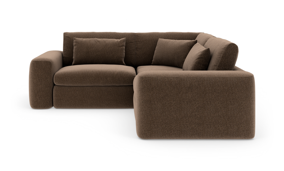 Brun L‑formet stofsofa med brede armlæn og flere puder, frilagt på hvid baggrund.