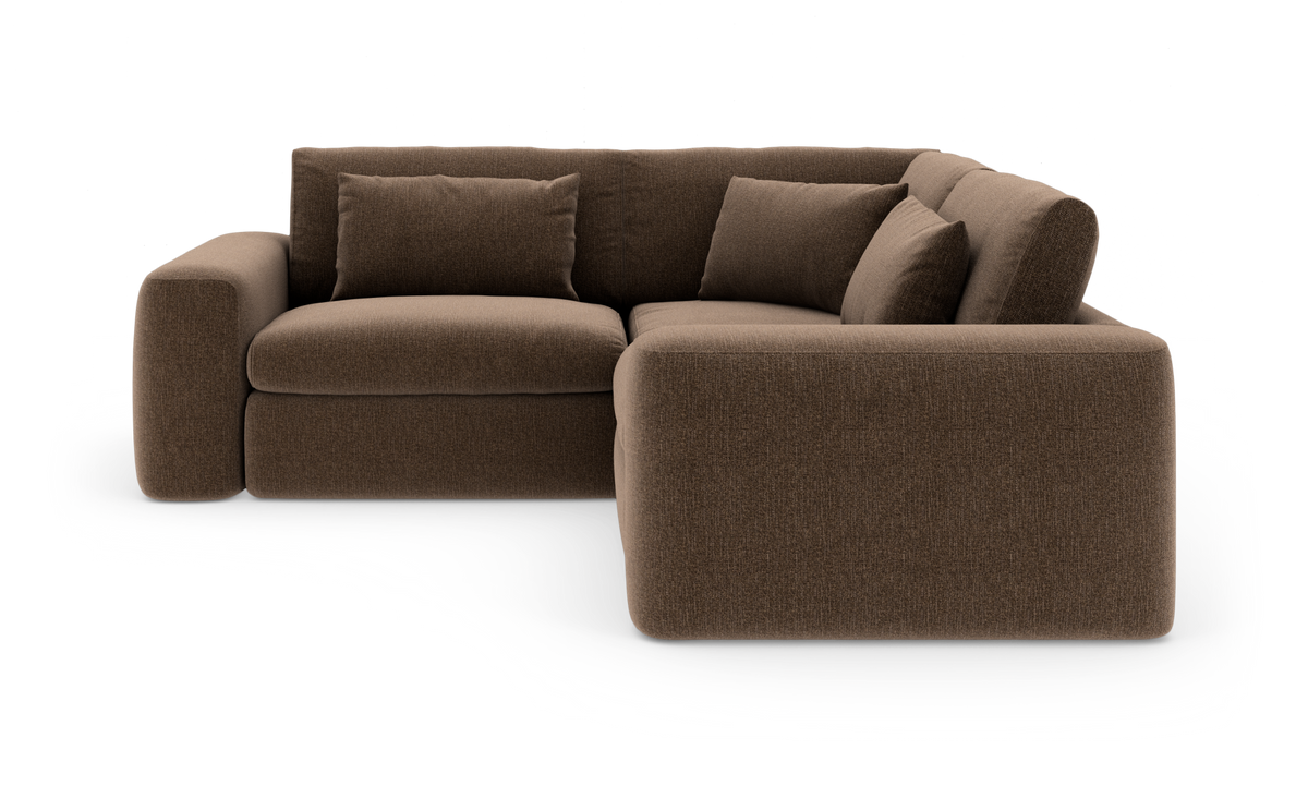 Brun L‑formet stofsofa med brede armlæn og flere puder, frilagt på hvid baggrund.