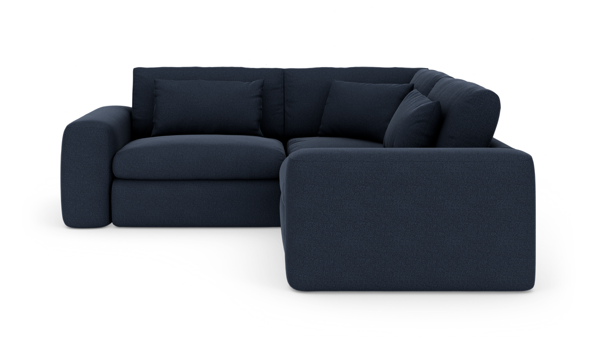 Mørkeblå L‑sofa med afrundede armlæn og løse ryghynder, fritlagt på hvid baggrund.
