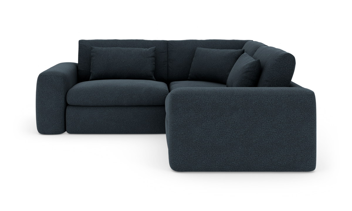 Mørkeblå L‑formet modulsofa med afrundede armlæn og løse ryghynder, fritlagt på hvid baggrund.