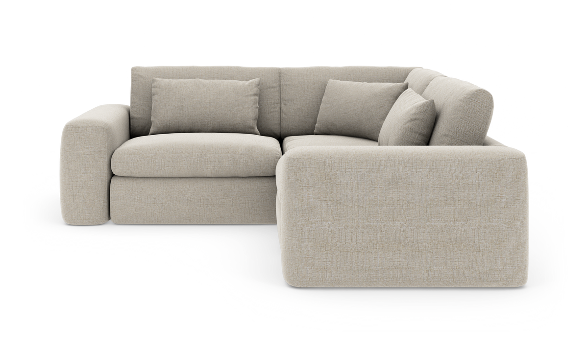 Beige L‑sofa med højrevendt chaiselong og løse puder, frilagt på hvid baggrund.