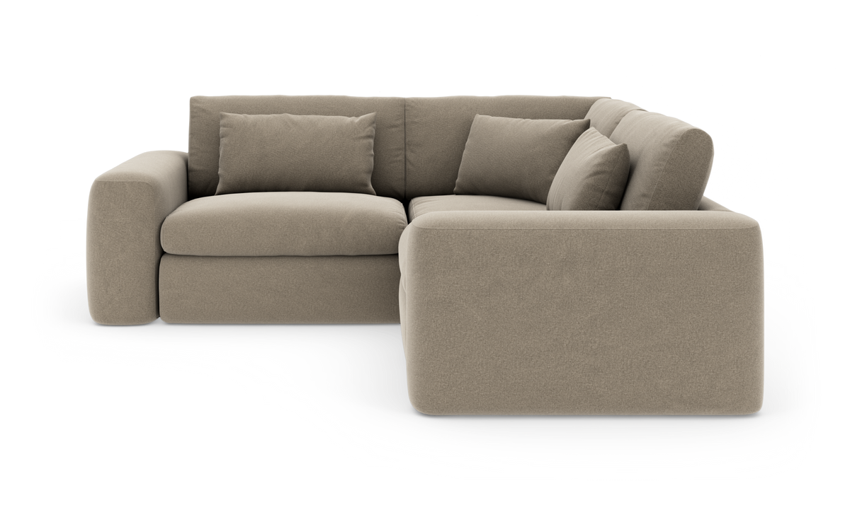 Beige hjørnesofa med chaiselong højre, bløde puder og afrundede armlæn, fritlagt på hvid baggrund.