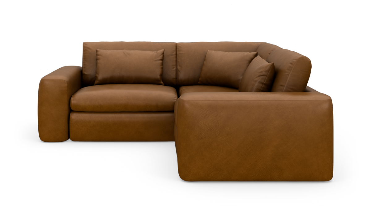 Brun læderhjørnesofa med chaiselong til højre og store puder.