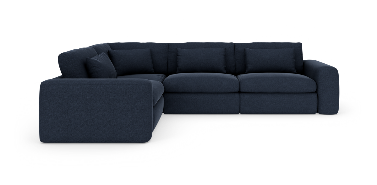 Marineblå modulær hjørnesofa med brede afrundede armlæn og løse ryghynder, frilagt på hvid baggrund.
