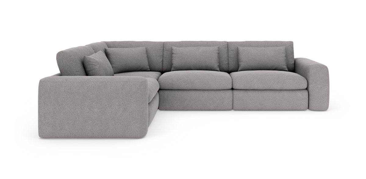 Lysegrå modulær hjørnesofa med brede armlæn og løse ryghynder, frilagt på hvid baggrund.