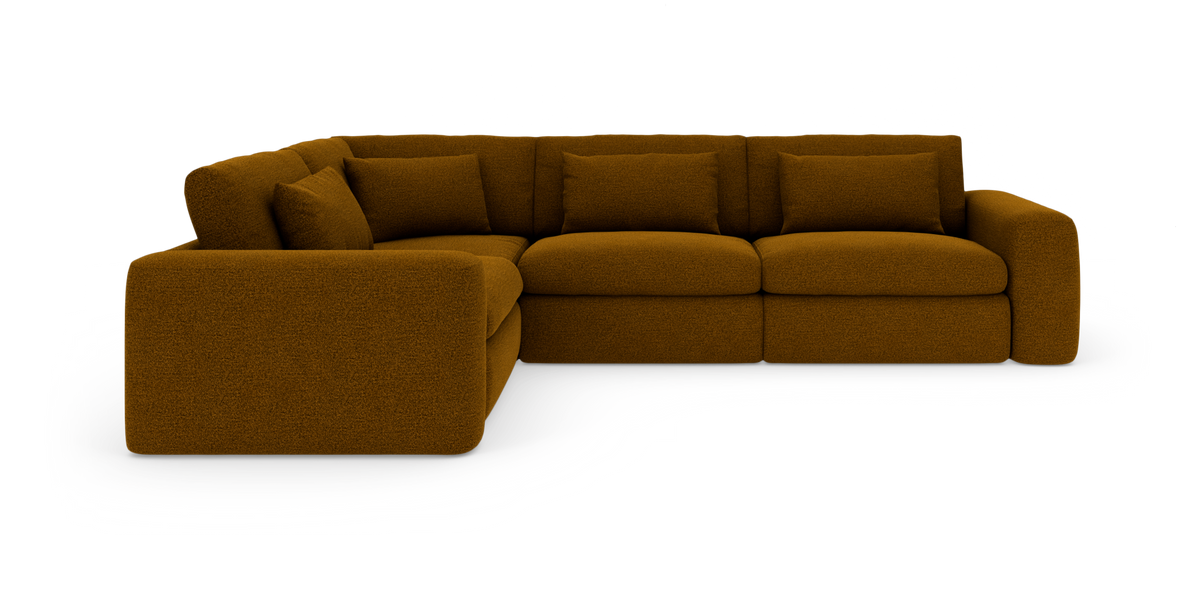 Modulær hjørnesofa i sennepsgul tekstil med bløde puder, vist på hvid studiebaggrund.