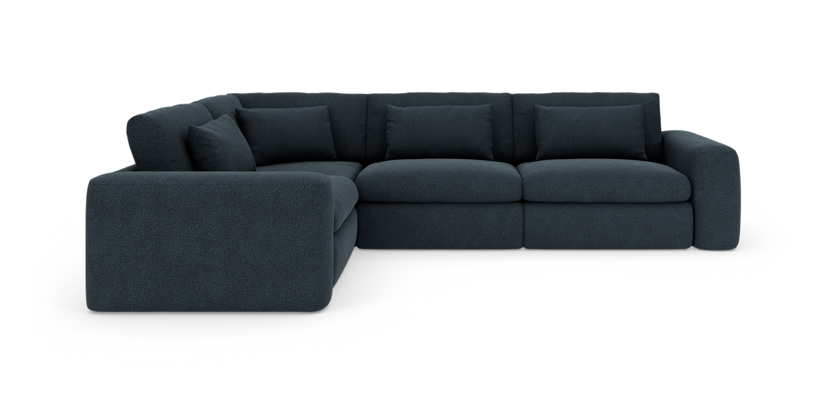 Mørkeblå modulær hjørnesofa med bløde, afrundede armlæn og løse ryghynder på hvid baggrund.