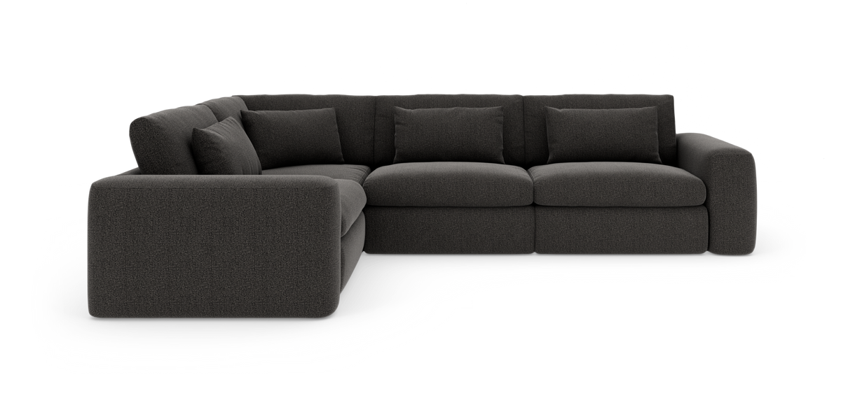 Mørkegrå modulær hjørnesofa med brede armlæn og løse ryghynder, vist fritlagt i vinkel.