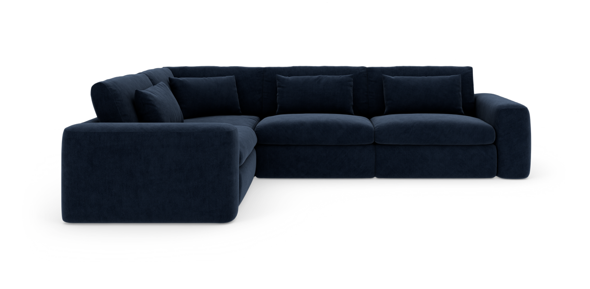 Mørkeblå hjørnesofa med bløde puder på hvid baggrund.