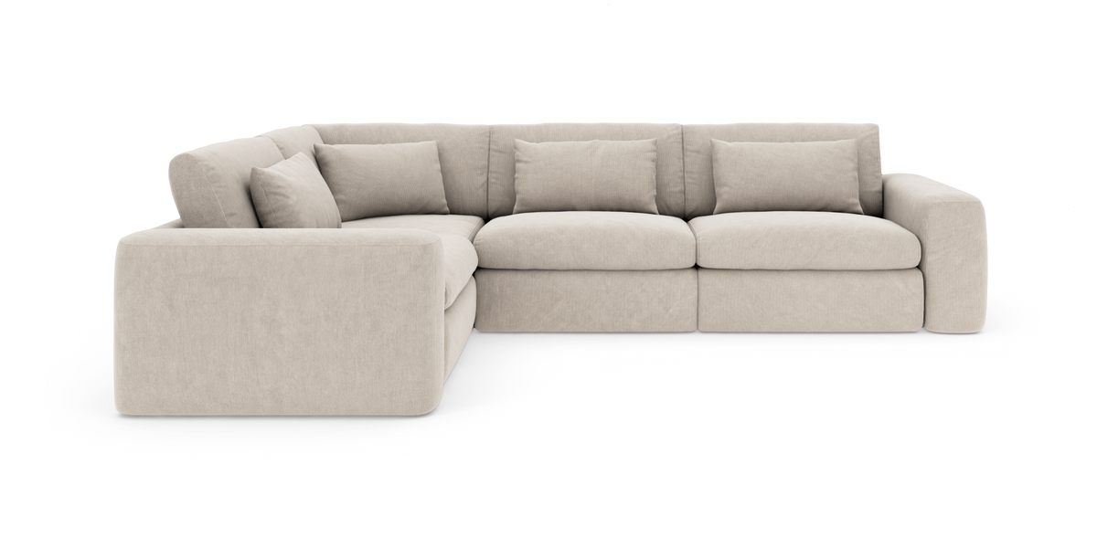 Beige modulær hjørnesofa med brede armlæn og løse ryghynder, set skråt forfra.
