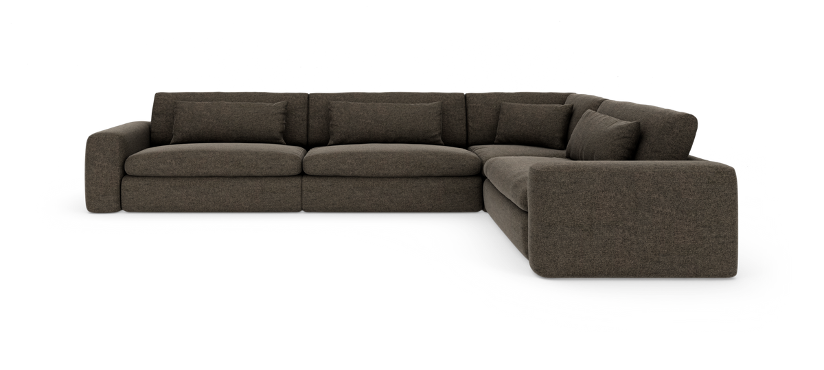 Mørkebrun hjørnesofa i stof med fyldige puder, frilagt på hvid baggrund.