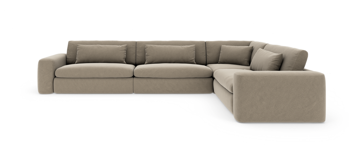 Beige L-formet modulsofa med brede armlæn og løse ryghynder på hvid baggrund.