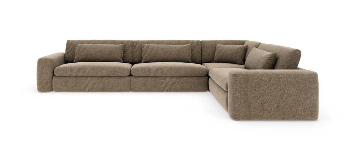 Brun L‑sofa i stof med afrundede armlæn og bløde ryghynder, vist i studie mod hvid baggrund.