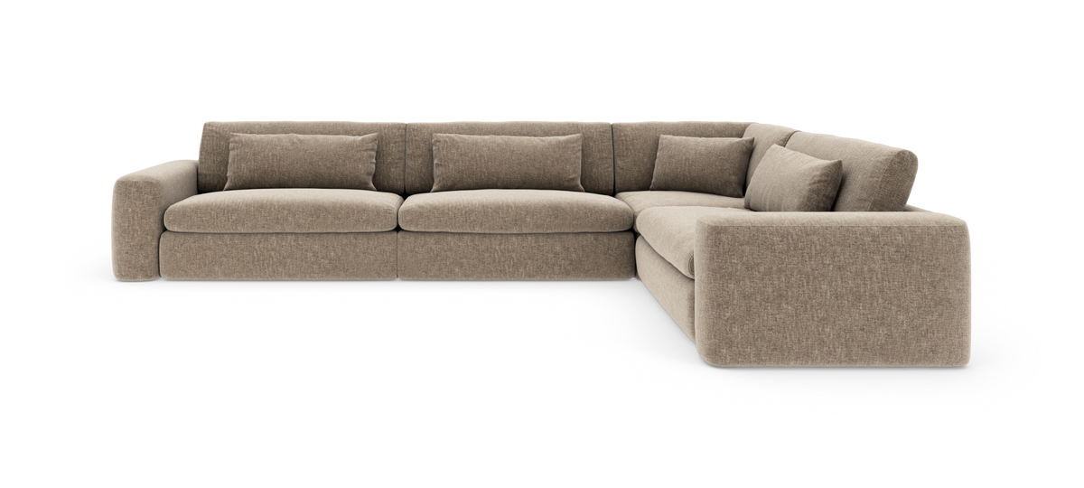Beige hjørnesofa i stof med afrundet hjørnemodul og løse ryghynder, vist i studie på hvid baggrund.