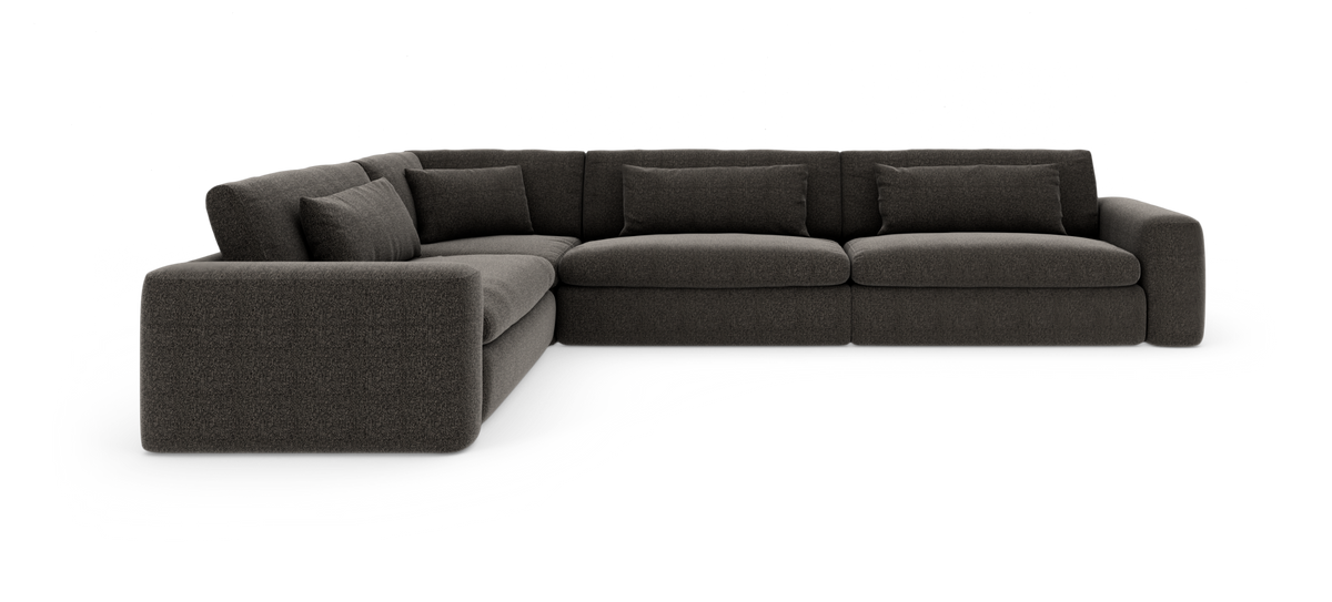 Mørkegrå L‑sofa med brede armlæn og løse ryghynder på hvid baggrund.