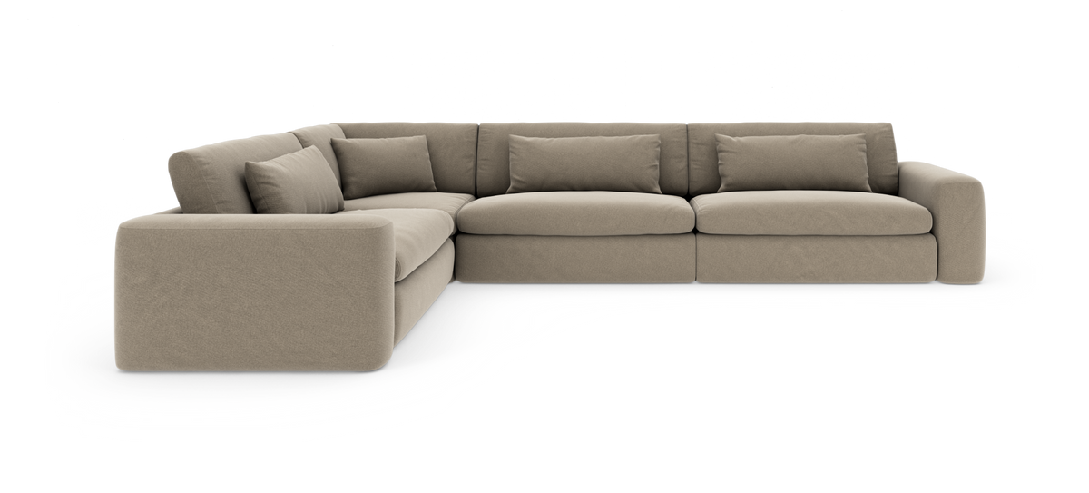 Beige modul-hjørnesofa med bløde sædehynder og puder, fotograferet mod hvid studiobaggrund.
