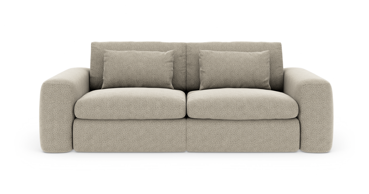 Beige stofsofa med afrundede armlæn og to løse ryghynder, fritlagt på hvid baggrund.