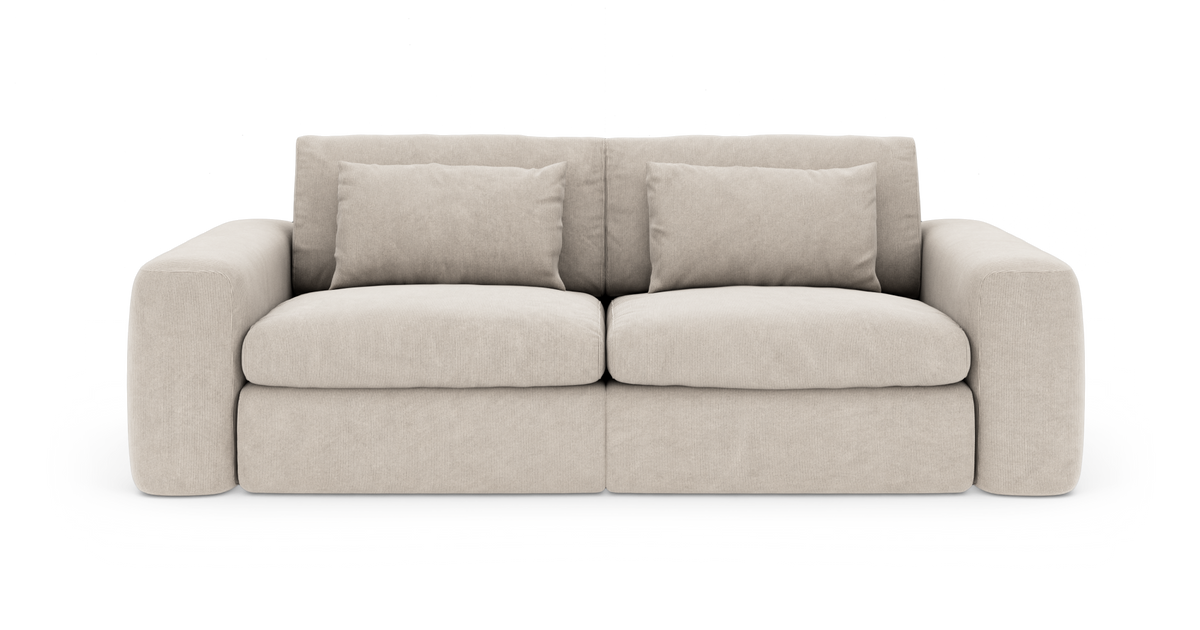 Beige sofa med brede armlæn, to sædehynder og løse puder, frilagt mod hvid baggrund.