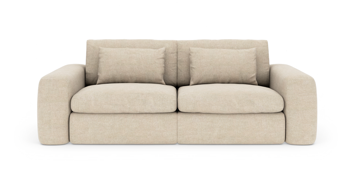 Beige 2-personers sofa med brede afrundede armlæn, tykke sædehynder og to løse ryghynder.
