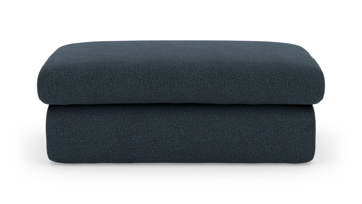 Mørkeblå stofpuf/fodskammel i moderne, minimalistisk design på hvid baggrund.
