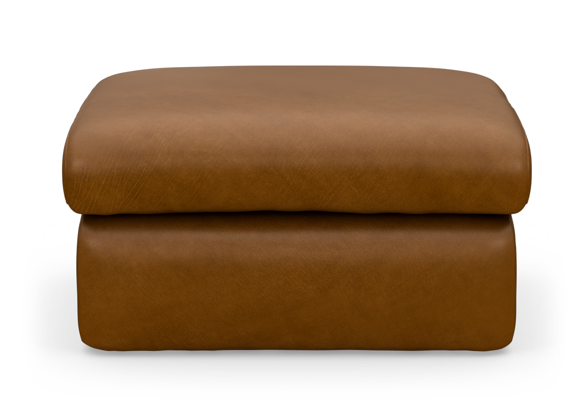 Brun læderpuf/ottoman med blød, kubisk form set lige forfra.