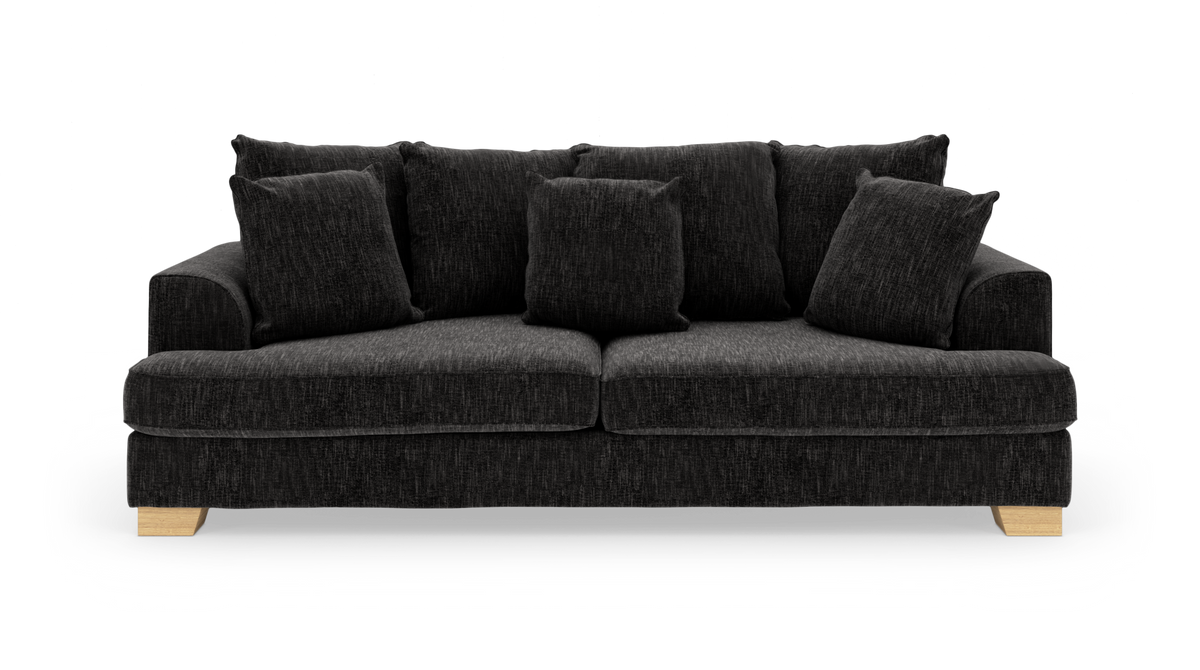 Mørkegrå stofsofa med fem løse puder og lyse træben, fotograferet forfra på hvid baggrund.