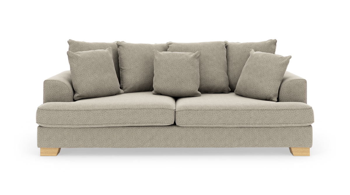 Beige sofa med syv løse puder og lyse træben, fritlagt på hvid baggrund.