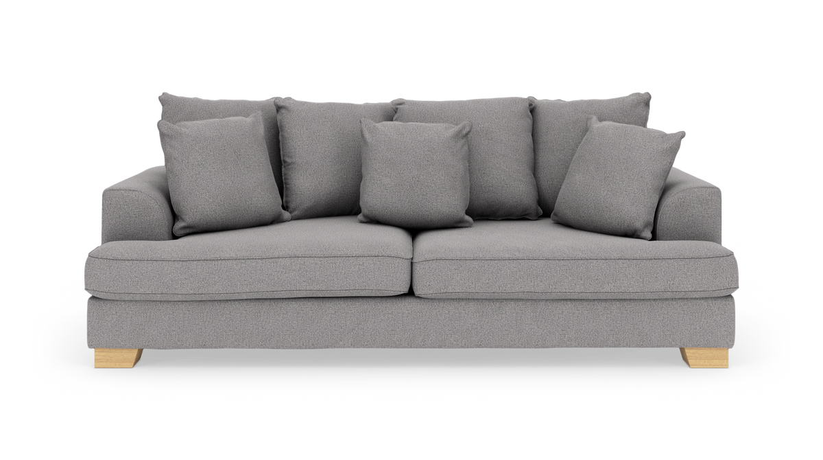 Grå stofsofa med syv løse puder og lyse træben, frilagt mod hvid baggrund.