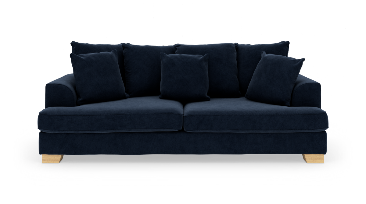 Mørkeblå sofa med fem løse puder og lyse træben, frilagt på hvid baggrund.