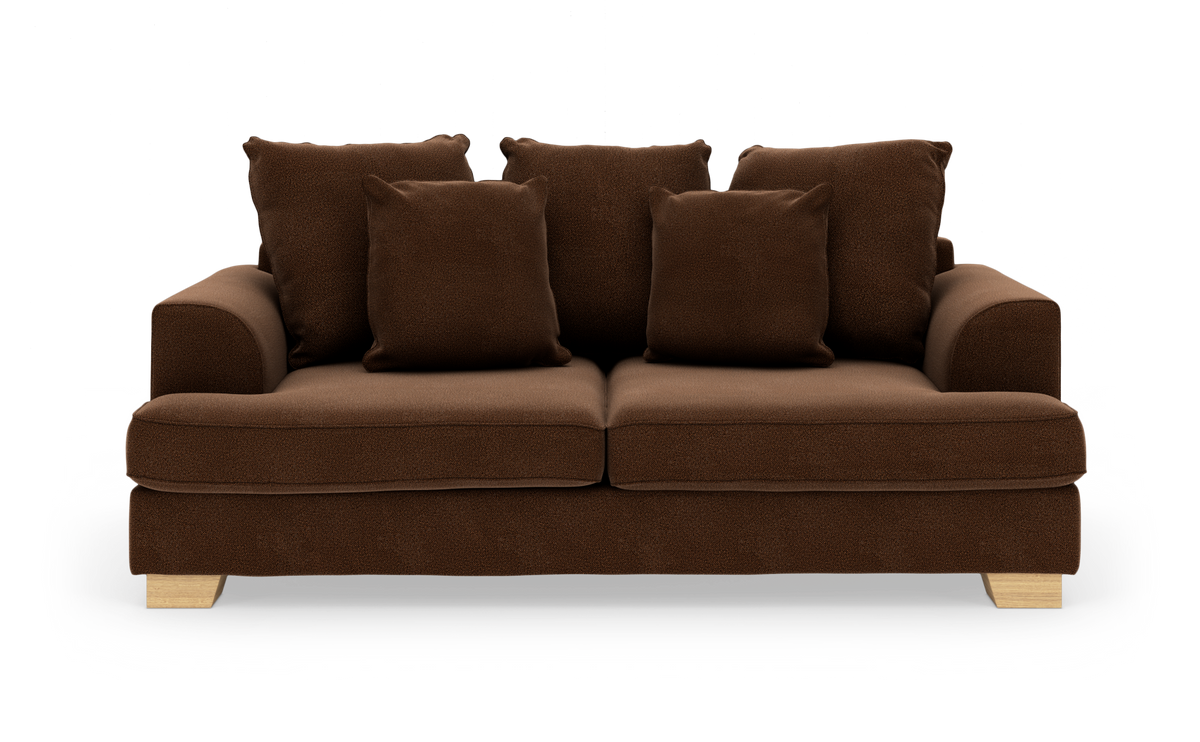 Brun sofa i blødt tekstil med fem puder og lyse træben, frilagt på hvid baggrund.