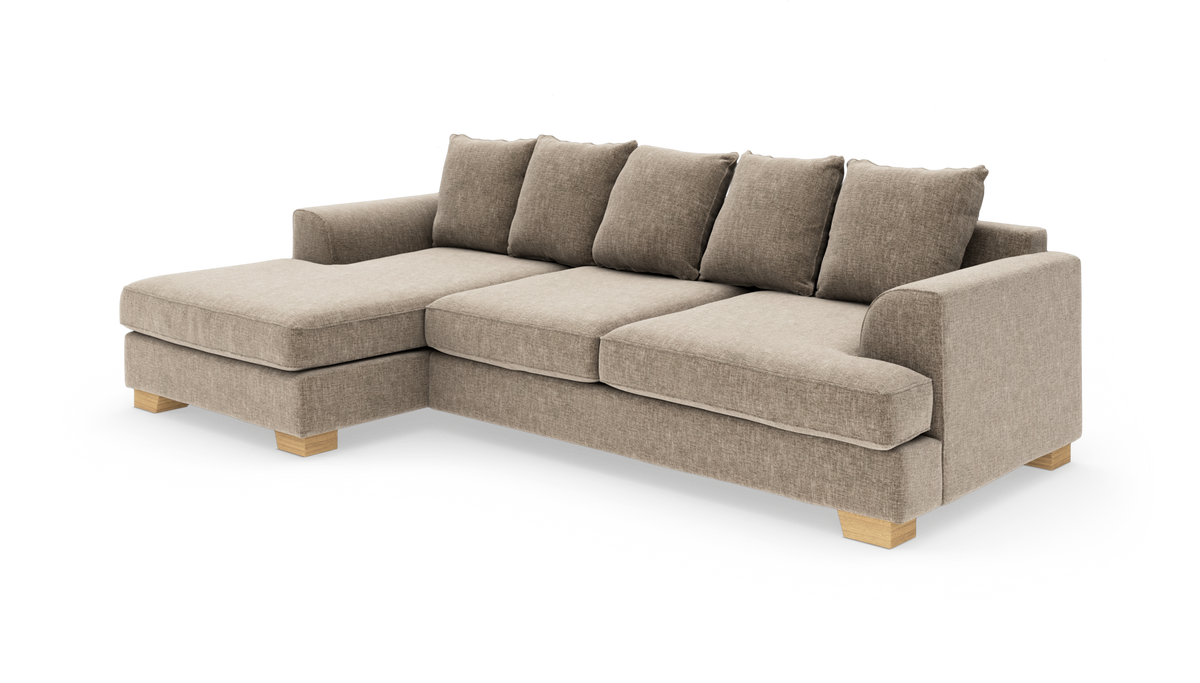 Beige L‑sofa med chaiselong til venstre, stofbetræk og træben; produktfoto på hvid baggrund.