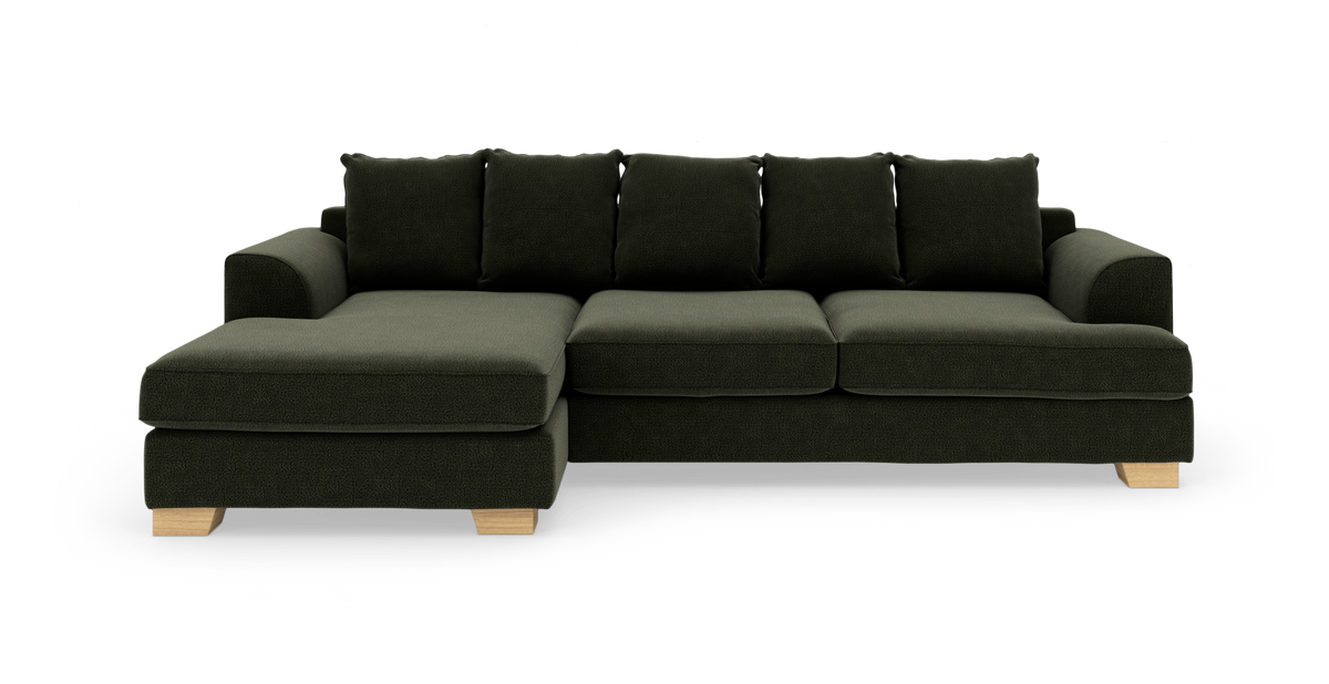 Mørkegrøn hjørnesofa med venstrevendt chaiselong, løse ryghynder og lyse træben, frilagt på hvid baggrund.